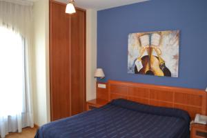a blue bedroom with a bed and a painting on the wall at Hostal Quevedo in León