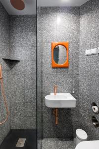 baño con espejo de color naranja y lavabo en urban beach sixties, en Portimão