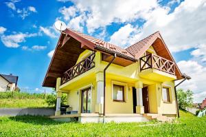 una pequeña casa amarilla con satélite en Domek Letniskowy Melon House en Gródek Nad Dunajcem