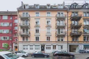 een hoog gebouw met auto's ervoor geparkeerd bij VISIONAPARTMENTS Albertstrasse - contactless check-in in Zürich