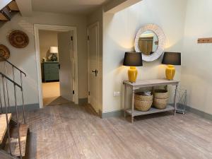 a hallway with a table with a lamp and a mirror at Rectory Farm Barn in Grantham