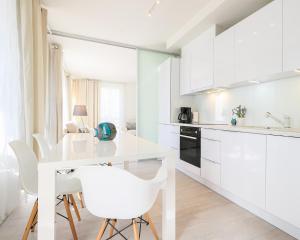 シフィノウイシチェにあるBaltycka 10 by Baltic Homeの白いキッチン(白いテーブルと椅子付)