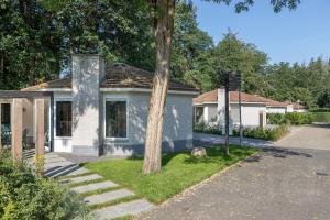 a small blue house with a tree in the yard at Bungalowpark Het Verscholen Dorp in Harderwijk