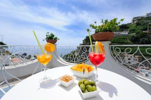 a table with three wine glasses and snacks on a balcony at Villa Guarracino Amalfi in Amalfi