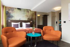 a hotel room with a bed and orange chairs at ProfilHotels Savoy in Jönköping