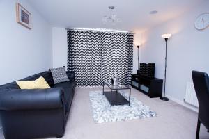 uma sala de estar com um sofá preto e uma mesa em Mills Apartment - Two bedroom en-suite apartment em Northampton