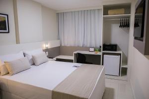 a bedroom with a large white bed and a desk at Trip Hotel Ubá in Ubá