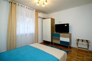 um quarto com uma cama e uma televisão de ecrã plano em White Stone em Sibiu