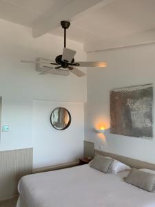 um quarto com uma cama branca e uma ventoinha de tecto em Hôtel Dolce Notte em Saint-Florent