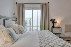 a bedroom with a white bed with a large window at Can Alberti 1740 Boutique Hotel in Mahón