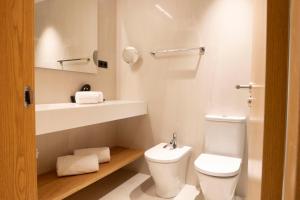 a white bathroom with a toilet and a sink at Goodnight Cádiz Apartments in Cádiz