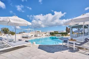 a swimming pool with white chairs and umbrellas at La Maison Private Villa in Agia Paraskevi