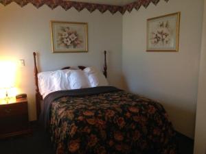 a hotel room with a bed with white sheets at Fred's Inn Restaurant & Lodging in Norwich
