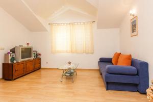 ein Wohnzimmer mit einem blauen Sofa und einem TV in der Unterkunft Holiday Home Beata in Trogir