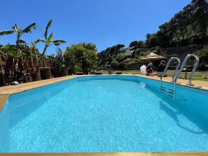 卡斯凱什的住宿－Quinta da Villa，一座大型蓝色游泳池,人们坐在雨伞下