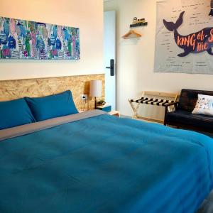 1 dormitorio con 1 cama azul y 1 silla en Lao Yu Homestay en Taitung