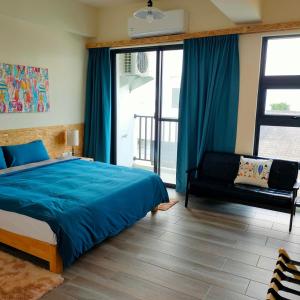 ein Schlafzimmer mit einem blauen Bett und einem Sofa in der Unterkunft Lao Yu Homestay in Taitung