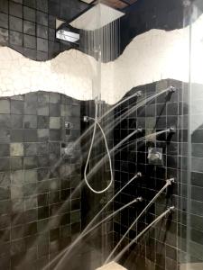 a shower in a bathroom with black and white tiles at Complejo Turístico La Garganta in El Chorro