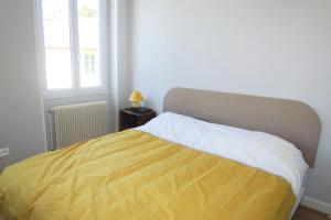 um quarto com uma cama com um cobertor amarelo e branco em Les Volets Bleus em Pierrefitte-sur-Loire