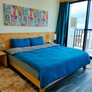 a bedroom with a blue bed and a large window at Lao Yu Homestay in Taitung City