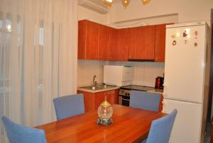 a kitchen with a wooden table and a white refrigerator at ILIADA Apartment in Litochoro