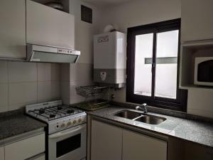 a kitchen with a stove and a sink and a window at Departamentos Illia By Lugar in Cordoba