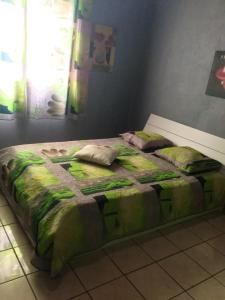 un letto con due cuscini sopra in una stanza di Villa chaleureuse près de Le Tampon avec piscine partagée a Le Tampon