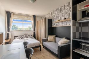 una camera da letto con un letto, un divano e una finestra di Studio Floréal - Welkeys a Lattes