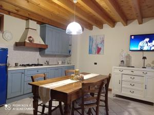 een keuken met een houten tafel met stoelen en een televisie bij CASA DELLE API in Pisogne
