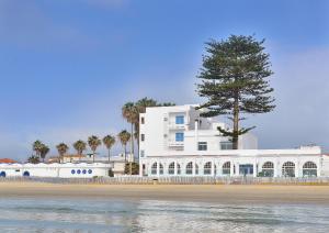 a white building on the beach with a tree at El Bahía Algeciras in Algeciras