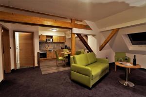 a living room with a green chair and a kitchen at Kelterhotel Fröscher in Forchtenberg