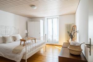 a white bedroom with a bed and a table at Rose Apartment by Quokka 360 - Refined Two-Bedroom Apartment with Garden in Lugano +24 photos