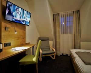 a hotel room with a desk and a tv on the wall at Kelterhotel Fröscher in Forchtenberg