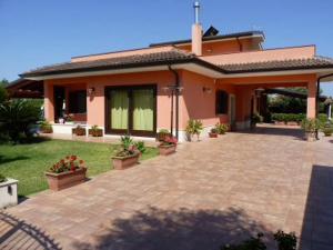 dom z ceglanym patio przed nim w obiekcie La stanza delle Muse in Villa con Piscina w mieście Fontane Bianche