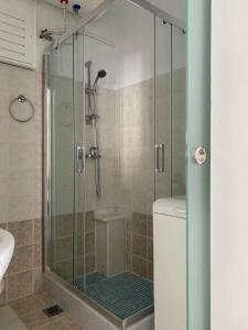 a shower with a glass door next to a toilet at Porto in Ermoupoli
