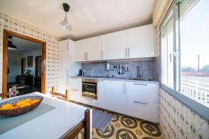 a kitchen with white cabinets and a bowl of oranges on a counter at Apartamento céntrico con vistas al mar in Villanueva de Arosa