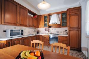 a kitchen with wooden cabinets and a table with fruit on it at Appartamento Del Veig in Cesenatico