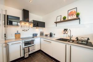 a kitchen with white cabinets and a sink at Proform Property Warehouse Apartments in Liverpool