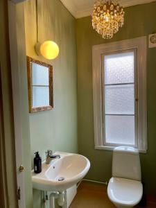 a bathroom with a sink and a toilet and a chandelier at Prästgatanett Apartments in Östersund