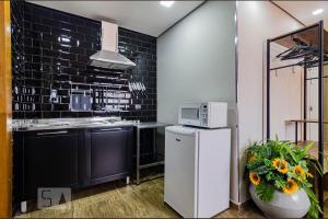 cocina con nevera blanca y microondas en A CASINA - STUDIOS Metrô FARIA LIMA, en São Paulo