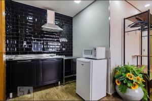 a kitchen with a white refrigerator and a microwave at A CASINA - STUDIOS Metrô FARIA LIMA in Sao Paulo