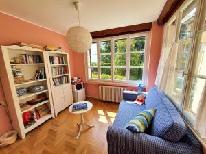 a living room with a blue couch and two windows at Villanuvola in Meina