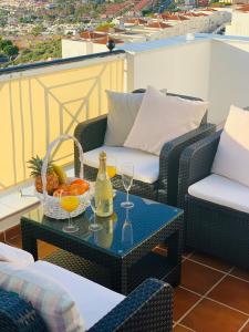 a patio with a table with drinks and a basket of fruit at Duplex Penthouse Panoramic Del Atlantico in Adeje