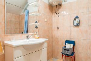 a bathroom with a sink and a mirror and a chair at Apartments Nina M in Baška Voda +76 photos