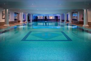 a large swimming pool with blue lights in a building at Leonardo Royal Hotel London City - Tower of London in London