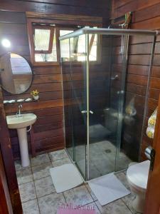 a bathroom with a glass shower and a sink at Hotel Fazenda Pintado na Brasa in Guararema