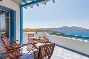 balkon ze stołem i krzesłami oraz oceanem w obiekcie Villa Blue Sky w mieście Trypiti