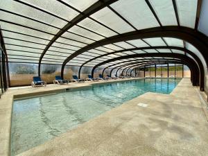 een binnenzwembad met stoelen en een groot zwembad met water bij Hotel Myriam Vias Plage in Vias