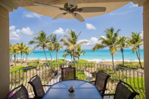 a dining room with a view of the beach and palm trees at Villa Renaissance Unit 205 Grace Bay Beach in Grace Bay