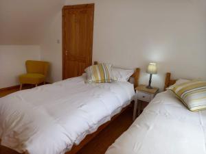 a bedroom with two beds and a yellow chair at Ard Na Mara Self Catering Isle of Mull in Dervaig